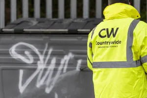 man removing graffiti from a bin