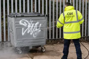 Man cleaning a bin of graffiti 