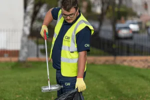 man litter picking into a black bin bag