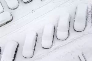 birds eye view of snow covered cars in car park